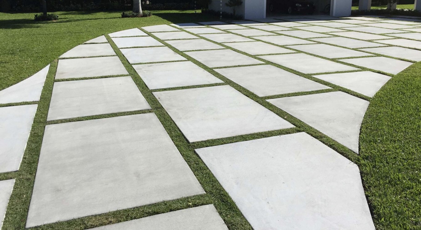 Decorative geometric concrete slab walkway set in a green lawn, showcasing stamped concrete work