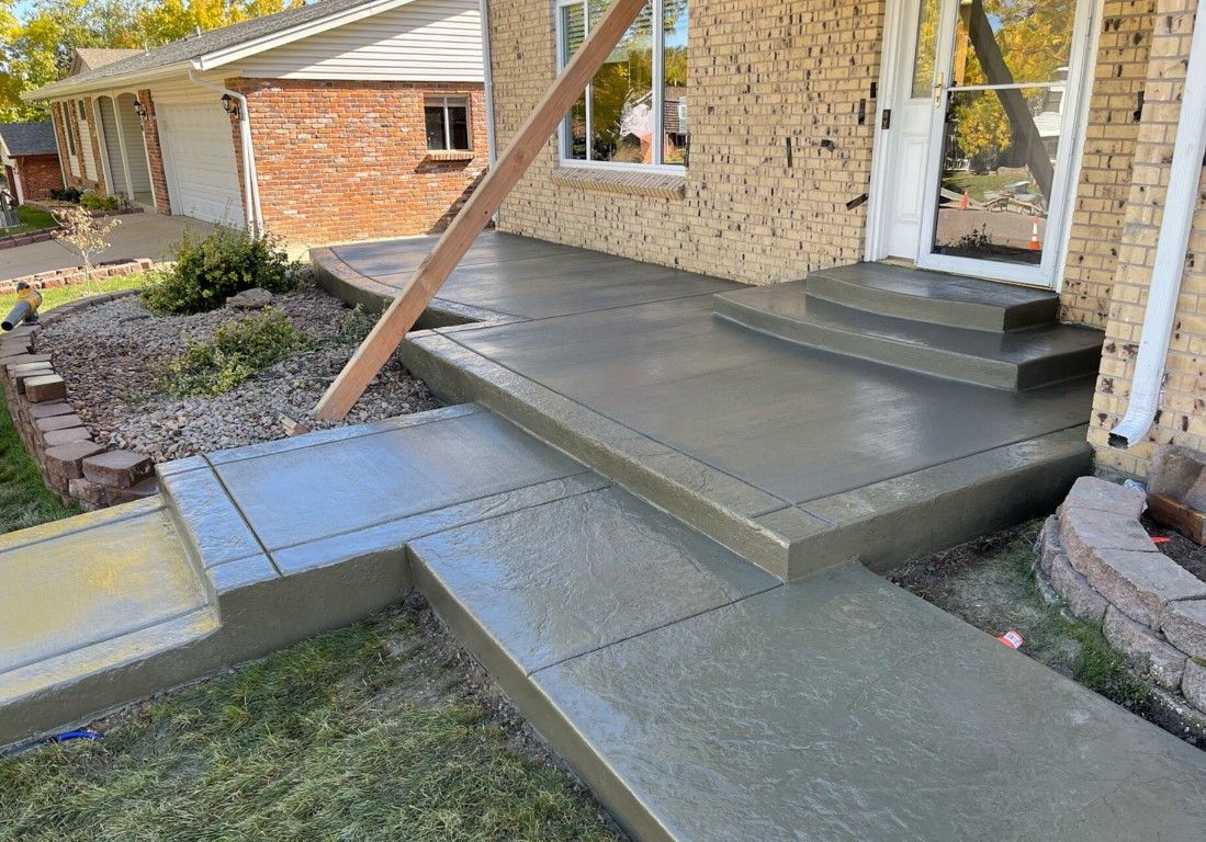 Newly installed stamped concrete patio with steps next to a brick house in South Dakota